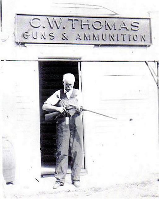 Man With Rifle Outside C.W. Thomas Guns and Almuni